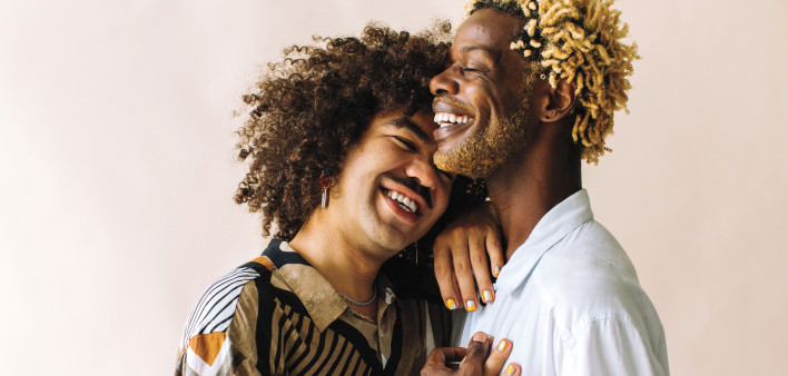 two gay men embrace and laugh