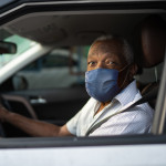 Portrait of senior african man driving a car with face mask