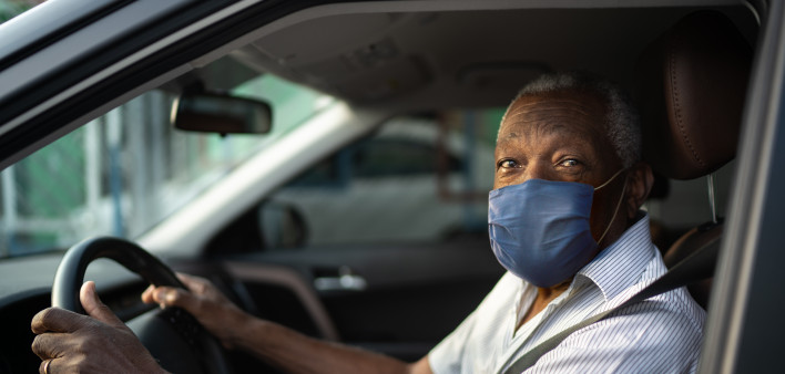 Portrait of senior african man driving a car with face mask