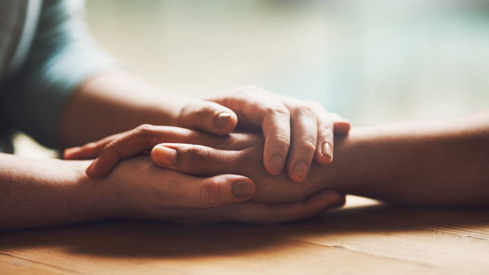 Shot of two people holding hands in comfort