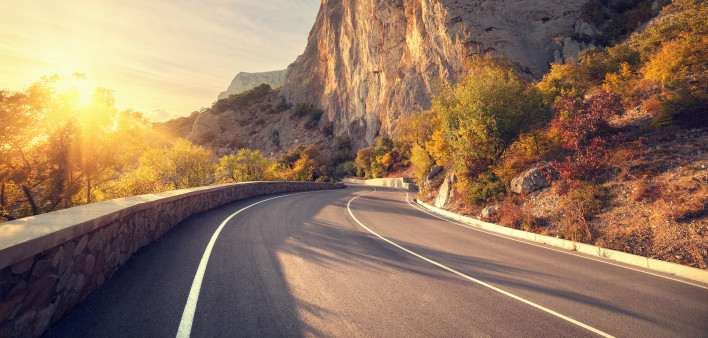 Asphalt road in autumn forest at sunrise. Crimean mountains