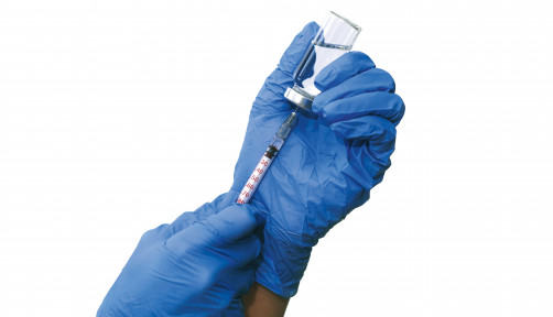 hands with blue gloved filling a syringe from a vial of vaccine