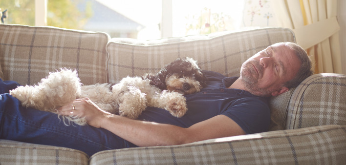 man sleeping on couch with his dog