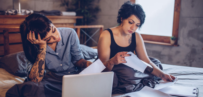 Frustrated lesbian couple calculating bills and tax expenses in bedroom