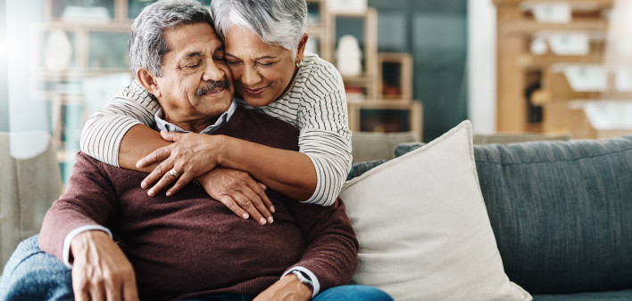 Cropped shot of a cheerful elderly woman hugging her husband who's in a wheelchair at home during the day