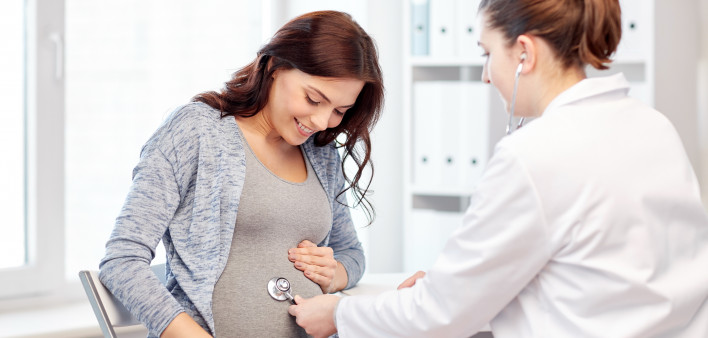 pregnancy, gynecology, medicine, health care and people concept - gynecologist doctor with stethoscope listening to pregnant woman baby heartbeat