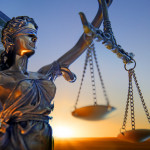 A statue of the blindfolded lady justice in front of the United States Supreme Court building as the sun rises in the distance symbolizing the dawning of a new era.