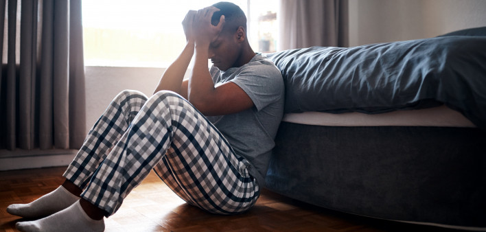 Full length shot of a handsome young man sitting at the foot of his bed and feeling depressed at home