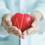 Female medical doctor holding red heart shape in hand with graphic of heart beat, cardiology and insurance concept