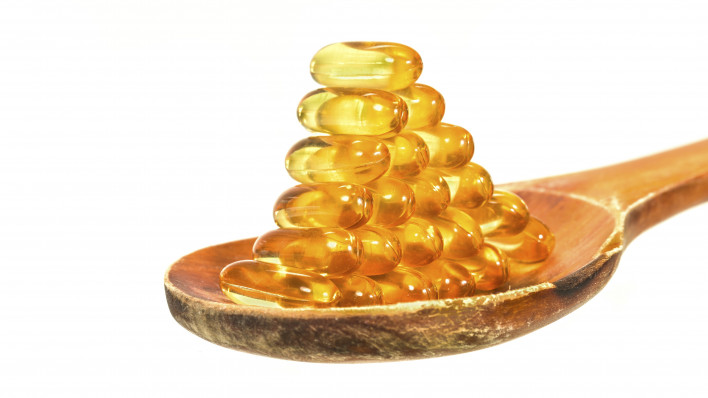 Vitamin D Capsules on wooden spoon