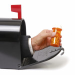 a hand holding a prescription coming out of a mailbox