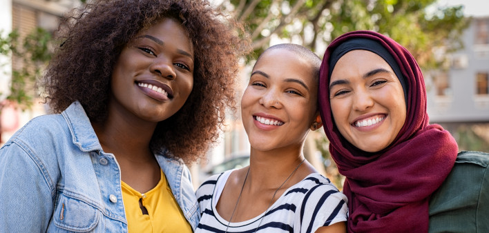 Group of three happy multiethnic friends looking at camera.