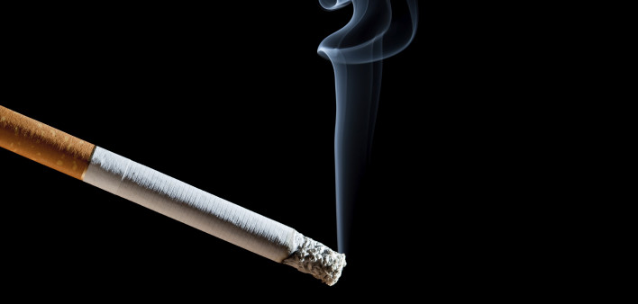 Cigarette with blue smoke on black background