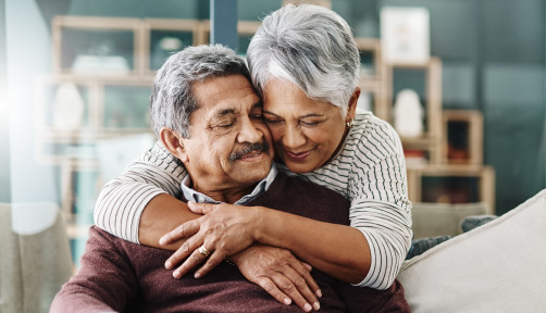 Cropped shot of a cheerful elderly woman hugging her husband who's in a wheelchair at home during the day
