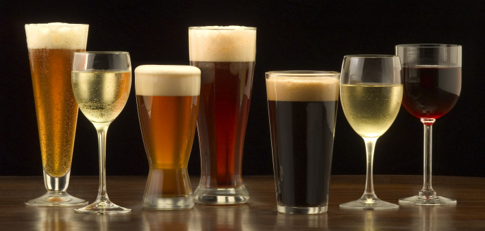 An assortment of glasses of wine and beer including a classic pilsner flute, a sparkling wine glass, an American half pint glass, a weizen or wheat beer glass, an American pint glass, a white wine glass, and a red wine glass.