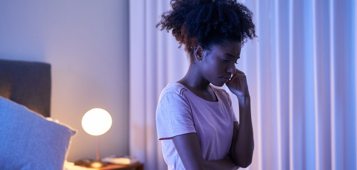 Cropped shot of a young woman sitting alone in her bedroom insomnia