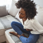 woman lying on her sofa alone and suffering from period cramps