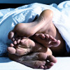 two pair of feet under covers in bed gay