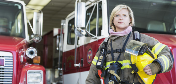 Female firefighter standing in front of fire truck