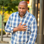 African American man having pains holding his chest.