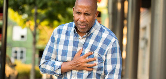 African American man having pains holding his chest.