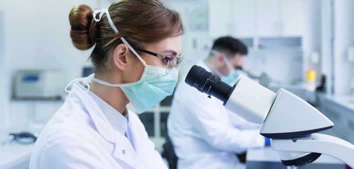 Team of experienced biologists working on microscopes in laboratory