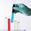 gloved hand holding test tubes with color liquid