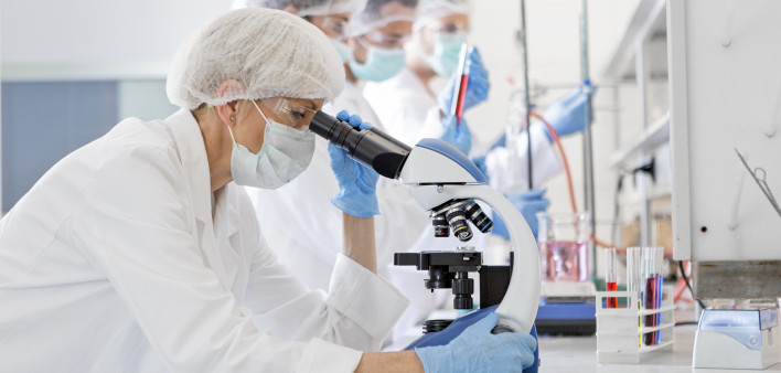Scientists in protective suits in a science laboratory study a virus