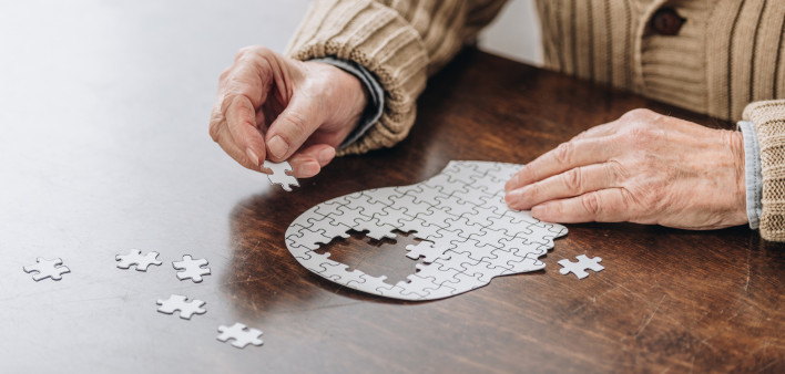 mans hands putting together puzzle pieces to make a head
