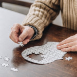 mans hands putting together puzzle pieces to make a head