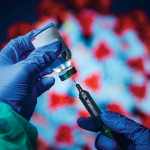 gloved hand needle vial vaccine coronavirus
