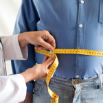 doctor measuring mans stomach
