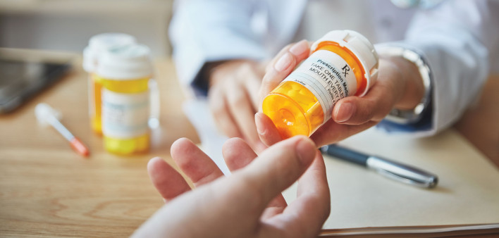 pharmacist hands bottle of pills to customer