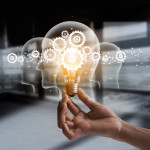illustration of hand holding light bulb over head shapes and cogs