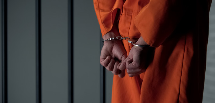 Prisoner with handcuffed arms behind back, another jail transfer, criminal