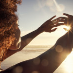 Rearview shot of a young woman blocking the sunlight with her hands at the beach