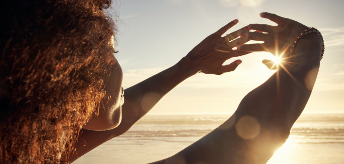 Rearview shot of a young woman blocking the sunlight with her hands at the beach