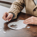 mans hands putting together puzzle pieces to make a head