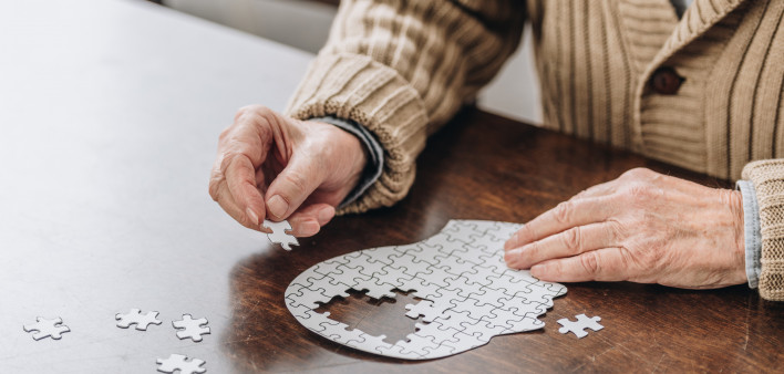 mans hands putting together puzzle pieces to make a head