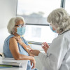 doctor giving older woman a shot vaccine