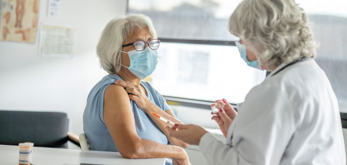 doctor giving older woman a shot vaccine