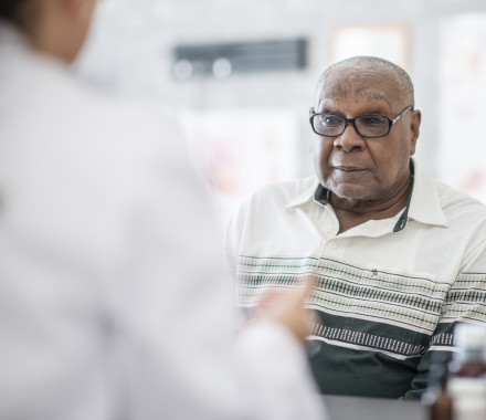 An African American man wearing eyeglasses sits in a doctor's office