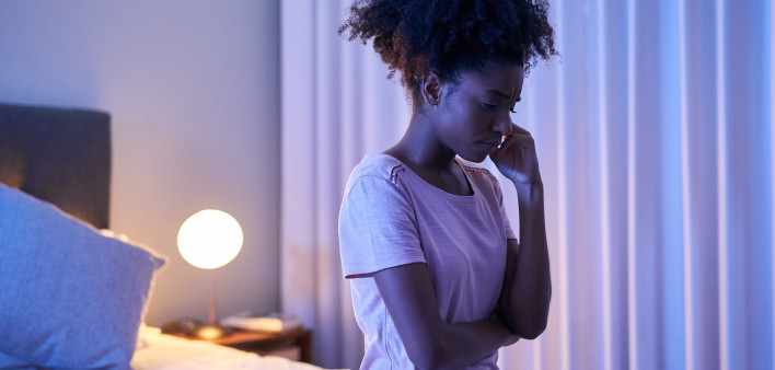 Cropped shot of a young woman sitting alone in her bedroom insomnia