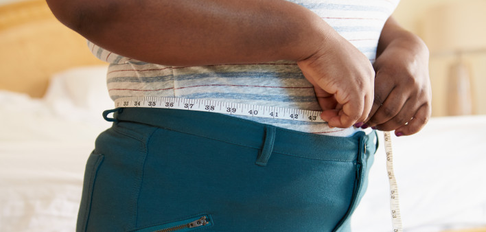 Close Up Of Overweight Woman Measuring Waist At Home Standing Still