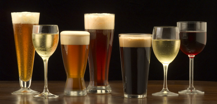 An assortment of glasses of wine and beer including a classic pilsner flute, a sparkling wine glass, an American half pint glass, a weizen or wheat beer glass, an American pint glass, a white wine glass, and a red wine glass.
