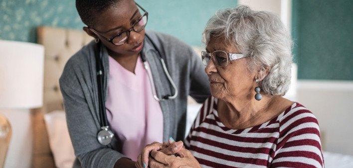 Black nurse comforts older woman