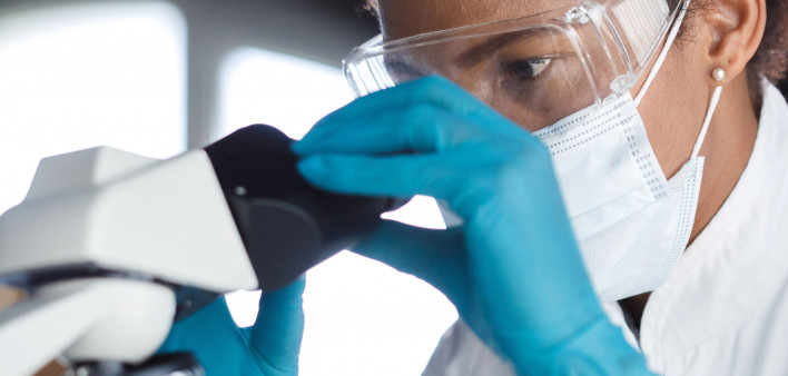 scientist looks through microscope