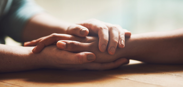 Shot of two people holding hands in comfort