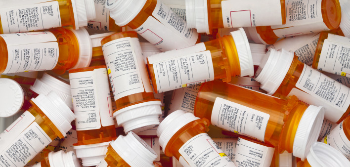Dozens of prescription medicine bottles in a jumble. This collection of pill bottles is symbolic of the many medications senior adults and chronically ill people take.