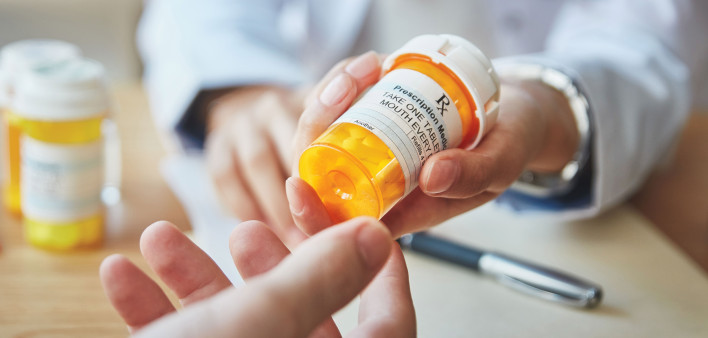 pharmacist hands bottle of pills to customer